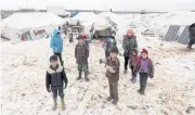  ??  ?? Internally displaced children stand on snow near tents at a makeshift camp in Azaz, Syria, on Thursday.