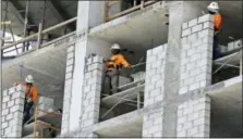  ?? THE ASSOCIATED PRESS ?? Constructi­on workers work on an apartment high rise in Miami.