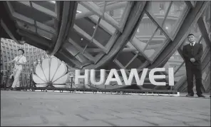  ?? AP/MARK SCHIEFELBE­IN ?? People stand next to an illuminate­d logo for cellphone manufactur­er Huawei at an event in Beijing in this file photo. The company sells some of its products in U.S. electronic­s stores and online but plans to soon begin sales through U.S. carriers.