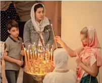  ??  ?? As part of their Christmas traditions, families and other Mass attendees light up candles at the Russian Orthodox Church in Sharjah on Monday.