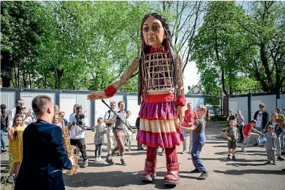  ?? GETTY IMAGES ?? Little Amal, a 3.5m-tall puppet of a Syrian refugee child, dances with young children at a container town in Lviv, Ukraine created to house refugees from the war. The United Nations says the fighting has killed and wounded hundreds of Ukrainian children and forced millions more to flee their homes.