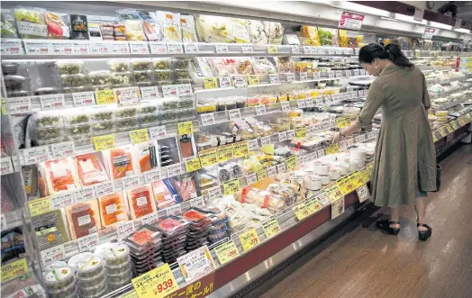  ??  ?? BUYER’S MARKET: A woman browses a dazzling array of goods at a convenienc­e store in Tokyo’s Roppongi district.