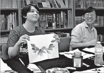  ?? MATTHEW PENNINGTON/AP ?? Student Moe Lewis, left, shows her watercolor painting of peony leaves at a traditiona­l Chinese painting class.