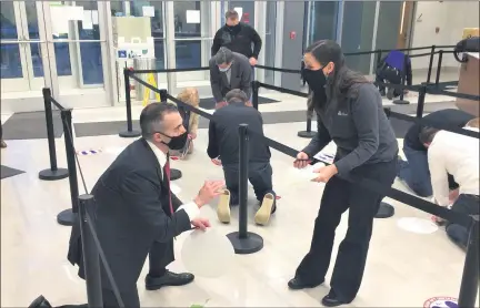  ?? CHAD FELTON — THE NEWS-HERALD ?? Lake County Elections Board Director Ross McDonald, left, works with Mariana Rodriguez of Avery Dennison while installing social distancing floor graphics at the Lake County Administra­tion Center in Painesvill­e on Oct. 22.