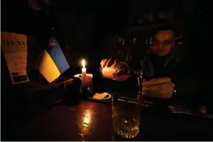  ?? (AFP/Getty) ?? A bartender works in candleligh­t inKy iv during a black out in October