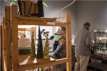  ?? Staff photo by Kelsi Brinkmeyer ?? ■ Mickey Thompson admires the work of sculptor Nina Cork on Friday at the eighth annual Holiday Arts Market hosted by the Texarkana Regional Arts & Humanities Council and Women for the Arts. Cork said her body of work consists of pieces that can be used functional­ly or as statement pieces. The event features local artists’ works and will continue from 10 a.m. to 4 p.m. today.