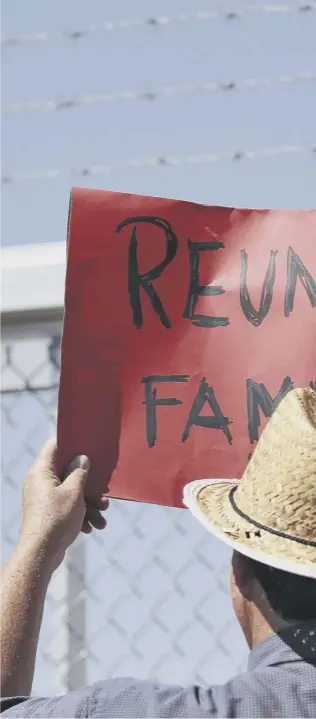  ??  ?? A protester holds a sign outside a closed gate at the Port of Entry facility in Fabens, Texas, where tent shelters are being used to house separated family members