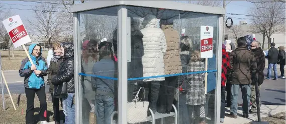  ?? NICK BRANCACCIO ?? Striking Jamieson workers cram into a bus shelter Sunday for warmth. Employees are picketing at the Jamieson facilities on Rhodes Drive and Twin Oaks Drive.
