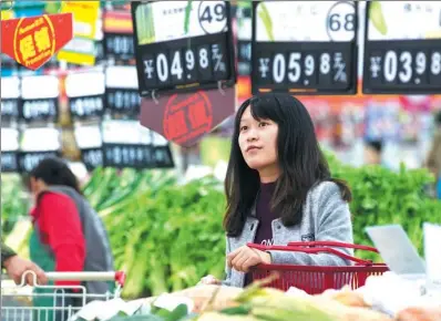  ?? SU YANG / FOR CHINA DAILY ?? A woman looks at vegetable prices at a supermarke­t in Nanjing, capital of Jiangsu province.