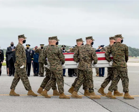  ??  ?? AFTERMATH
Right, from top: Nancy and Ronald Reagan at a memorial service for soldiers killed in the 1983 Beirut bombing; President John Kennedy awaiting developmen­ts during the 1962 Cuban missile crisis. Above: At Dover Air Force Base in Delaware, Marines carry the remains of fellow Marine Darin T. Hoover, killed in the Kabul airport attack.