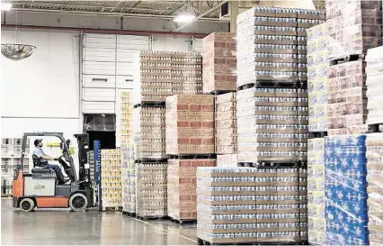  ?? Craig Hartley photos ?? Forklift operator Alfonso Montoya works among mountains of beer at Houston Distributi­ng.