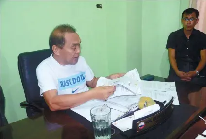  ?? SUNSTAR FOTO / ALAN TANGCAWAN ?? SUSPENDED. Ermita Barangay Captain Felicisimo Rupinta reads the papers containing his suspension from the Department of Interior and Local Government.