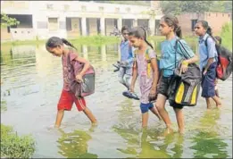  ?? BHARAT BHUSHAN/HT ?? Children walking on a ground inundated with rainwater mixed with sewage, leaking from a septic tank, to reach Government Elementary School on the outskirts of Kalar Bheni village, 12km from Patiala, on Tuesday. This has been their routine for the past one month.