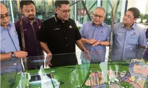 ??  ?? Homes for many: Dzulkefly (centre) looking at the master plan models of Bandar Tiram after officiatin­g its sales gallery.