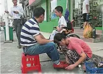  ??  ?? 田秀銀帶上患病兒子，在街頭替人擦皮鞋。