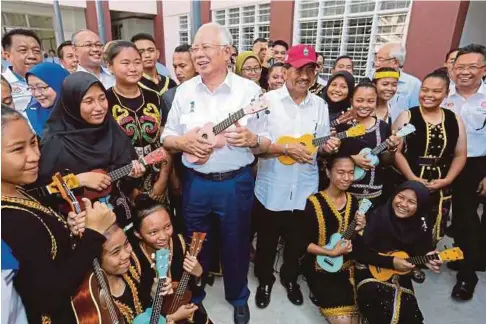  ??  ?? NAJIB dan Musa bermain ukulele bersama pelajar pada tinjauan mesra di bangunan baru SMK Pekan Telipok, semalam.