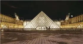  ?? — AFP ?? People stand outside the Louvre Museum at night on Friday in Paris after a French soldier patrolling at the Louvre shot and seriously injured a machete-wielding attacker earlier.