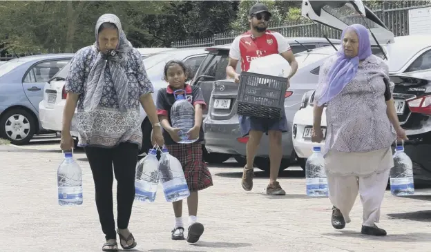  ?? PICTURE: ANWA ESSOP/AP ?? People carry water collected from a natural spring in Cape Town, as shortages begin to affect daily life in the city