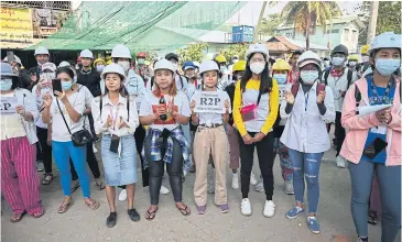  ??  ?? NO BACKING DOWN: Protesters wearing hard hats hold a demonstrat­ion against the military coup in Yangon yesterday.