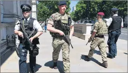  ??  ?? Soldiers joined police on patrol in London’s Whitehall while heavily armed officers, right, were patrolling popular beaches such as the one in Scarboroug­h yesterday