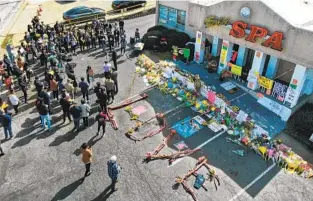  ?? CHANG W. LEE NYT ?? Mourners gathered at a makeshift memorial in the parking lot of the Gold Spa in Atlanta for the eight people who were killed during attacks on three Atlanta-area spas on March 21, 2021.