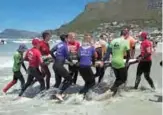  ??  ?? Pamela Hanford, 75, is helped by a team of coaches and volunteers out of the water after surfing at an adaptive surfing event at Muizenberg beach.