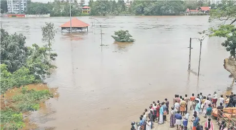  ??  ?? People stand on the steps of Aluva Shiva Temple complex submerged in water after the opening of Idamalayar dam shutter following heavy rains, on the outskirts of Kochi, India. — Reuters photo