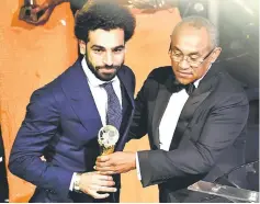  ??  ?? Confederat­ion of African Football (CAF) president Ahmad Ahmad presents The African Footballer of the Year Award to Egypt and Liverpool striker Mohamed Salah during an award ceremony at the Internatio­nal Conference Centre in Accra. — AFP photo