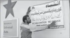  ??  ?? QUETTA
A worker busy in pasting a warning banner for corona vaccinated or without vaccinated customer that no vaccinatio­n no service on the wall at Petrol Pump near Jinnah Road. -APP