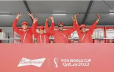  ?? Claudio Villa / Getty Images ?? Workers at the Budweiser stand pose at a fan festival before the World Cup. Qatar banned beer sales at the stadiums.