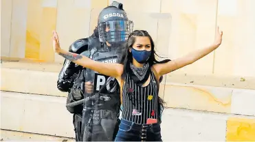  ??  ?? Una manifestan­te del pasado lunes protege con su cuerpo a un integrante del Esmad en Bogotá.