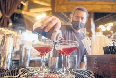  ?? MARKMIRKO/HARTFORD COURANT ?? Butchers and Bakers’ Nick Tiberio mixes drinks at the restaurant’s bar in Farmington. Starting Friday, Connecticu­t restaurant­s will be allowed to operate at 100% capacity with some social-distancing restrictio­ns still in place.