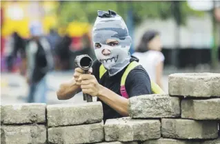  ?? efe / jorge torres ?? Un joven con la cara tapada y un lanza morteros posa para una fotografía en una barricada en el barrio indígena de Monimbó en la ciudad de Masaya.