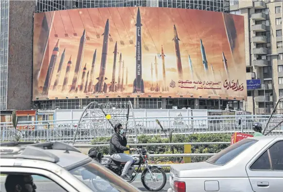  ?? PICTURE: ATTA KENARE/AFP VIA GETTY IMAGES ?? A billboard in central Tehran shows named ballistic missiles with a caption reading ‘Israel is weaker than a spider’s web’