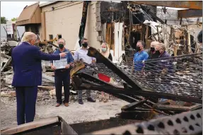  ??  ?? The Associated Press
President Donald Trump talks to business owners Tuesday as he tours an area damaged during demonstrat­ions after a police officer shot Jacob Blake in Kenosha, Wis.