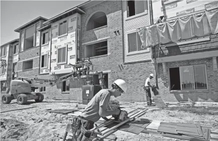  ?? DANIEL ACKER/BLOOMBERG FILE ?? Joe Genusa cuts siding at an apartment building under constructi­on in Peoria, Ill. The Biden administra­tion wants to award grants and tax credits to cities that improve equitable access to affordable housing.