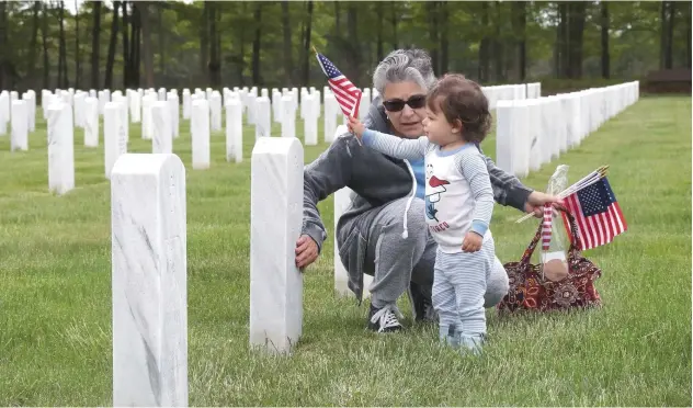  ?? Agence France-presse ?? ↑
A woman and a child visit Calverton National Cemetery in Wading River, New York, on Saturday.