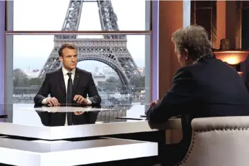  ??  ?? Macron (left) poses on the TV set before an interview with RMC-BFM French journalist Jean-Jacques Bourdin (right) at the Theatre national de Chaillot in Paris, after United States, Britain and France decided to launch air strikes in Syria in response...
