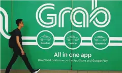  ??  ?? A man walks past a Grab office in Singapore.