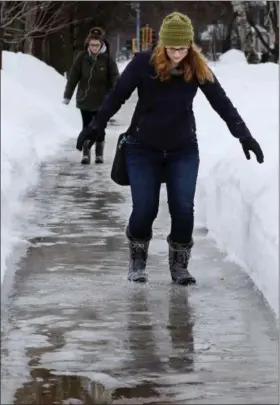  ?? DAN REILAND — THE EAU CLAIRE LEADER-TELEGRAM VIA AP ?? University of Wisconsin-Eau Claire student Kaylee Stuttgen of Fall Creek, Wis., steadies herself through ice and puddles as she walks along Garfield Ave. to school in Eau Claire, on Wednesday.