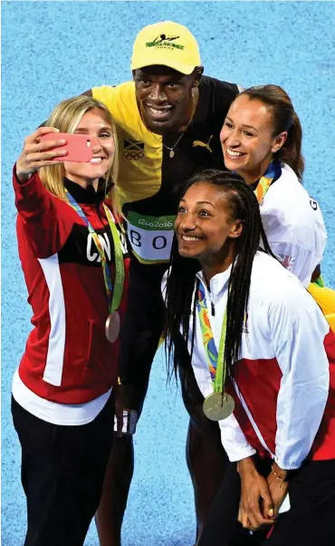  ??  ?? Egal was drum herum passiert, Usain Bolt gehört die gesamte Aufmerksam­keit: Auch die erstplatzi­erten Siebenkämp­ferinnen wollten nach ihrer Siegerehru­ng sofort ein Selfie mit dem jamaikanis­chen Olympiasie­ger über 100 Meter.