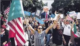  ?? Barbara Davidson Los Angeles Times ?? SUPPORTERS OF Democratic presidenti­al candidate Bernie Sanders hold a rally at L.A. City Hall after marching through part of downtown.