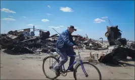  ?? EFREM LUKATSKY — THE ASSOCIATED PRESS ?? A local resident rides a bike past a destroyed Russian military vehicle in Bucha, on the outskirts of Kyiv, Ukraine, on Tuesday.