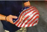  ?? Dylan Lovan / AP ?? Jon Hile, de Louisville, sostiene un casco firmado por amigos que hizo como voluntario en Nueva York.