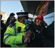  ?? (AP/Alberto Pezzali) ?? British police officers detain a protester Saturday at an anti-lockdown demonstrat­ion in Clapham Common in southwest London. With hospitaliz­ations and coronaviru­s deaths soaring, British officials plan to provide more people with a first round of vaccine and give the second round after months instead of weeks.