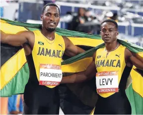  ??  ?? Jamaica’s Ronald Levy (right) and Hansle Parchment celebrate with the national flag after capturing gold and silver, respective­ly, in the men’s 110 metres hurdles final at the 2018 Commonweal­th Games in Gold Coast, Australia.