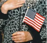  ??  ?? Emilia Segura, of Petaluma, originally from Mexico, holds a miniature American flag during Thursday’s naturaliza­tion ceremony in Oakland.