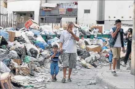  ?? MOHAMED AZAKIR / REUTERS ?? Ciudadanos beirutíes pasan al lado de basuras abandonada­s en plena calle