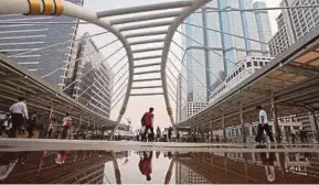  ?? BLOOMBERG PIC ?? Commuters walking on a pedestrian bridge in Sathorn business district in Bangkok. King Maha Vajiralong­korn increased his control over Crown Property Bureau in July last year.