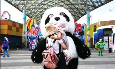  ?? Photo: cnsphoto ?? A young mother holds her child and interacts with a staffer dressed as a giant panda at Happy Valley Wuhan on Tuesday, the first day of the theme park’s reopening as the COVID-19 epidemic ebbs in Wuhan, Central China’s Hubei Province.